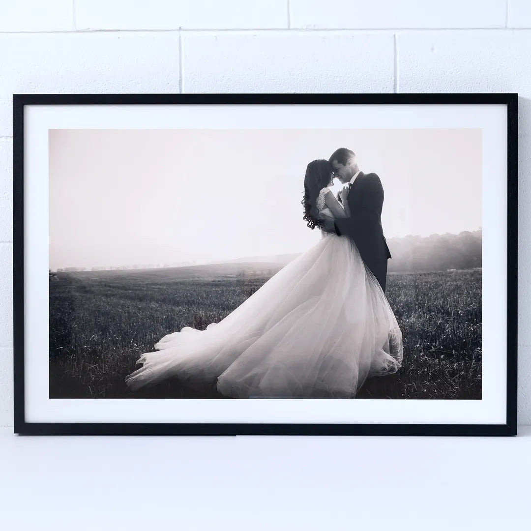 Framed black and white photograph of a couple embracing in a field.